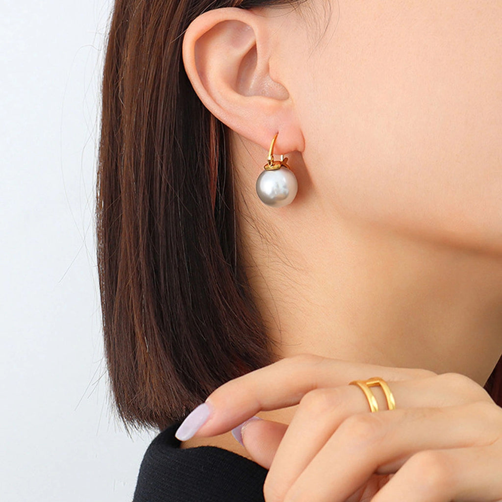 Pearl earring worn by a person with a plain background