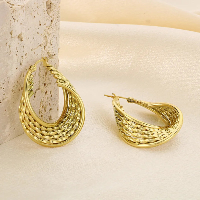 Gold hoop earrings on a textured beige surface