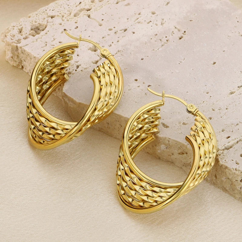 Gold hoop earrings on a textured beige surface