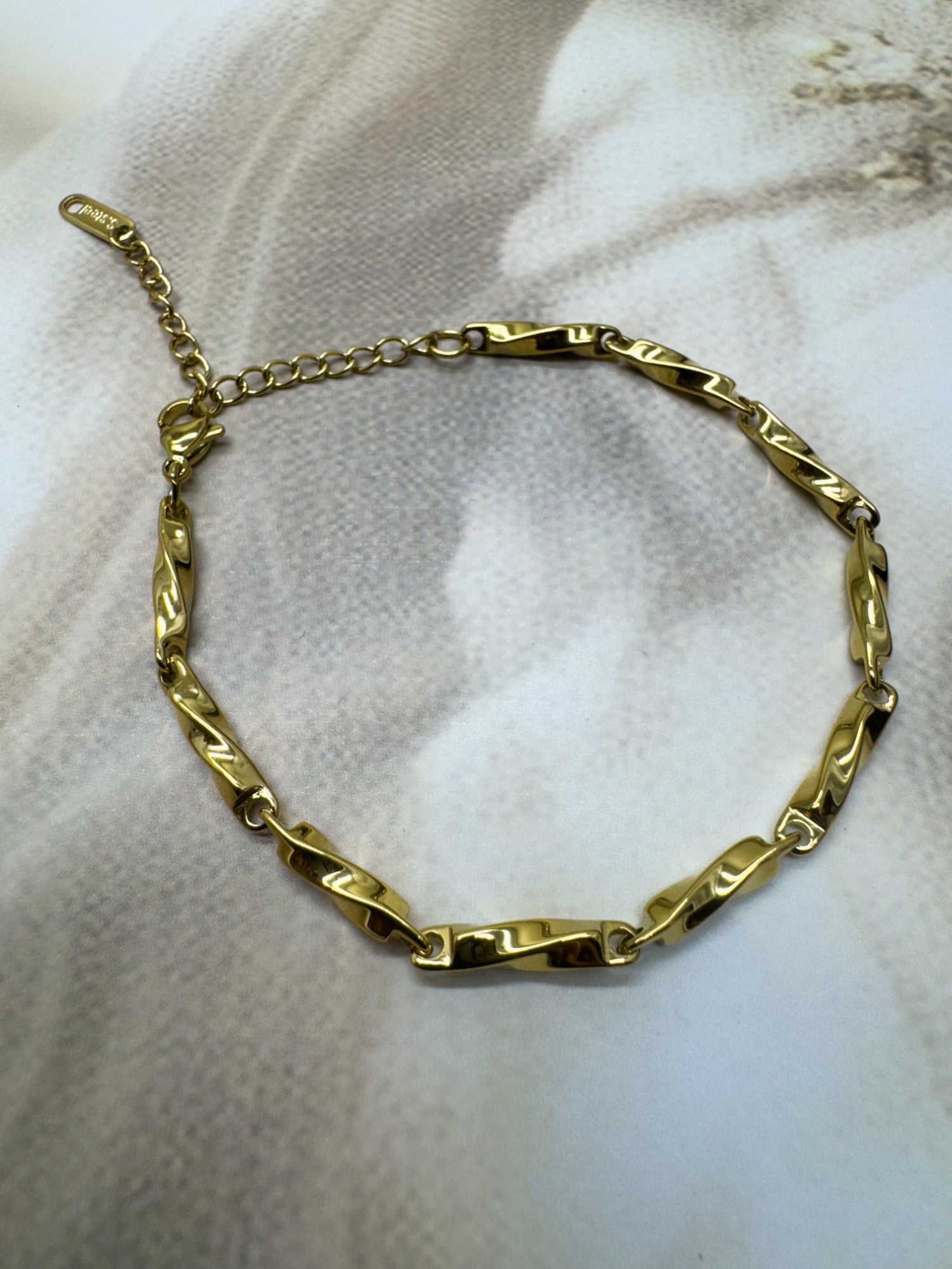 Gold chain bracelet on a textured white surface