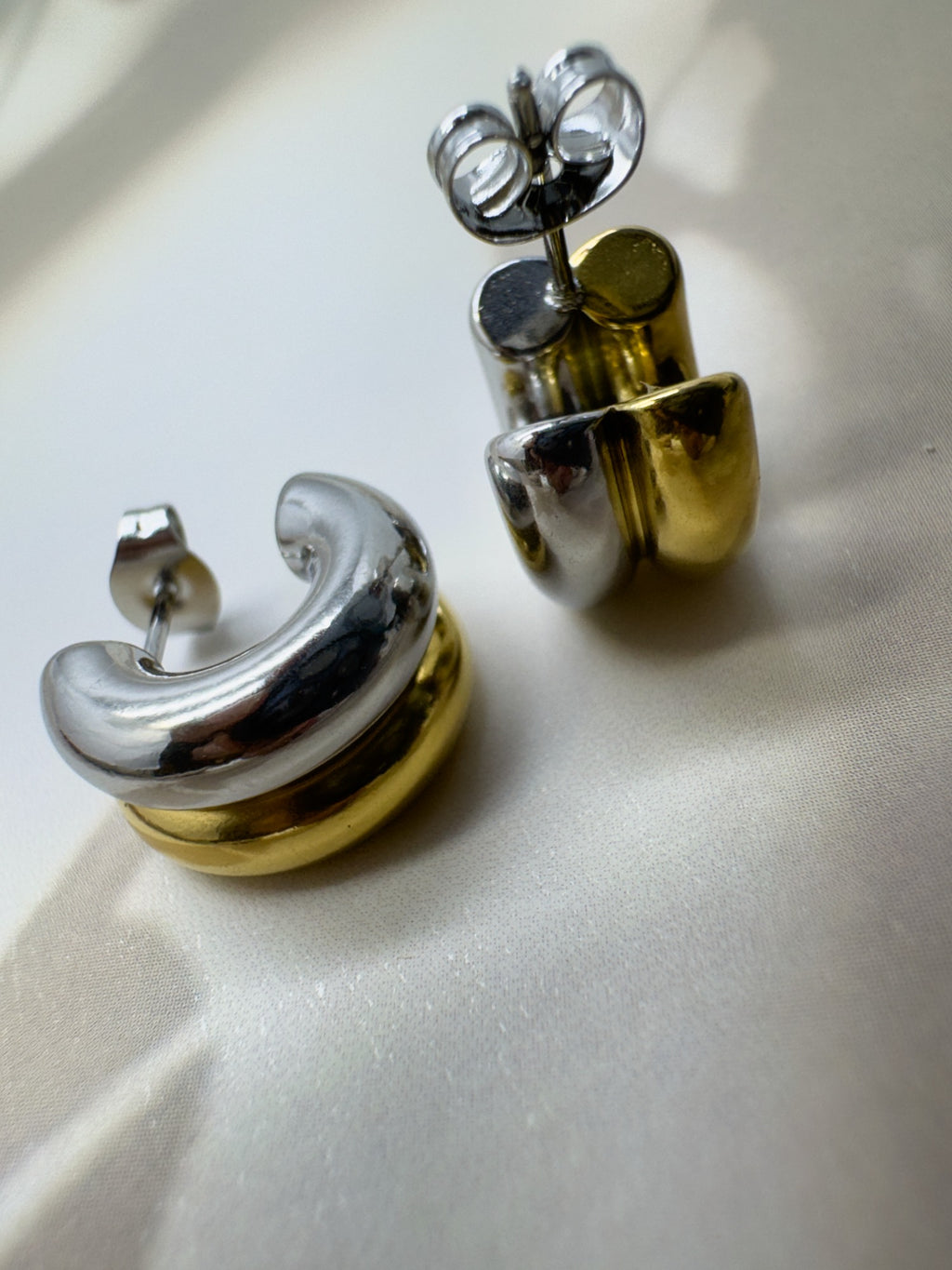 Pair of gold and silver earrings on a light background